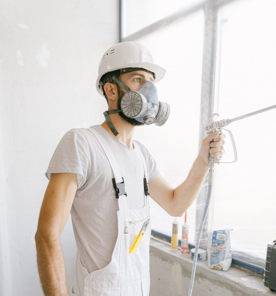 commercial painting Construction worker wearing safety gear and painting indoors.