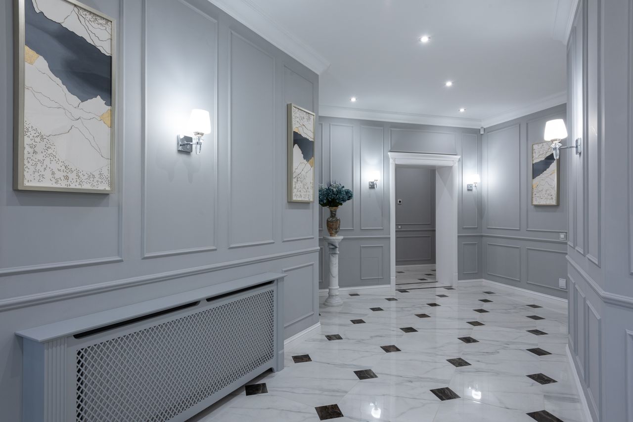 Interior of corridor of contemporary villa with shiny tiled floor and gray walls decorated with paintings and lamps