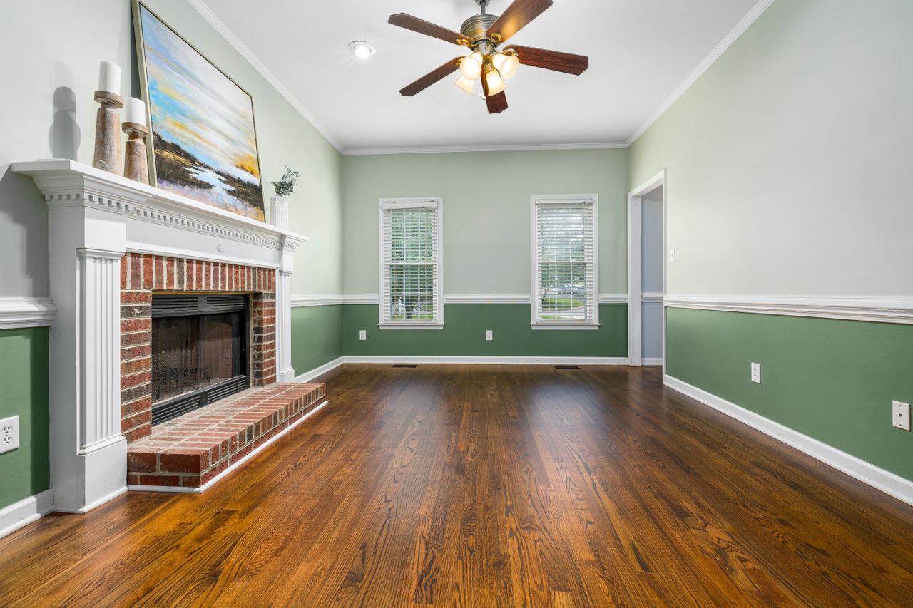 services-01 A cozy empty living room featuring a brick fireplace, wooden floors, and elegant decor.